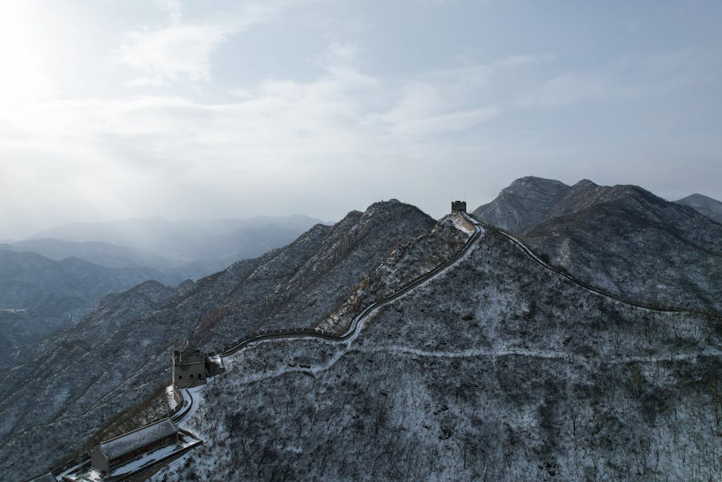 Stunning aerial view of the Great Wall of China covered in snow against a blue sky in winter.
