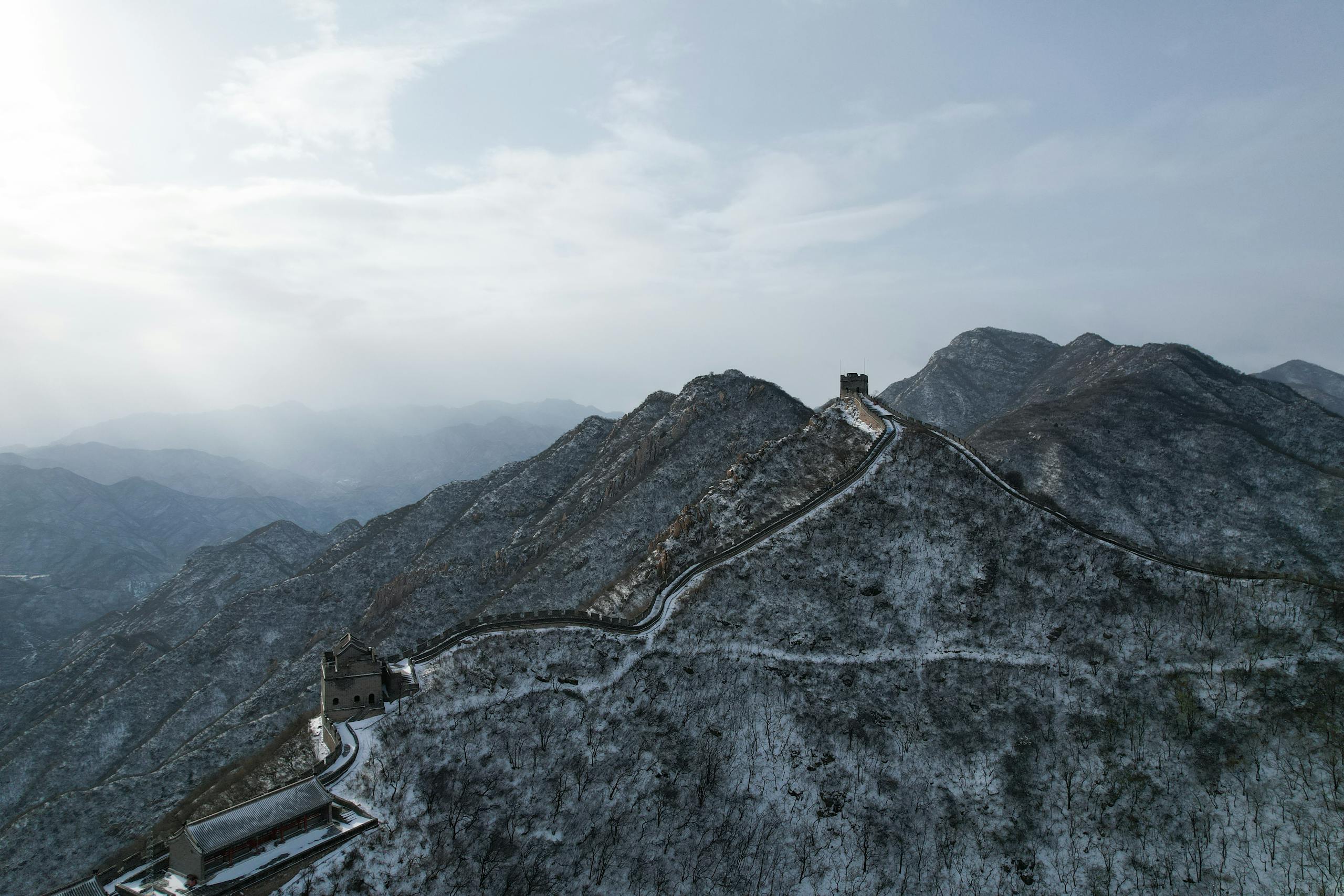 Stunning aerial view of the Great Wall of China covered in snow against a blue sky in winter.